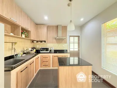 Modern kitchen with wooden cabinets and black countertops in a bright home interior