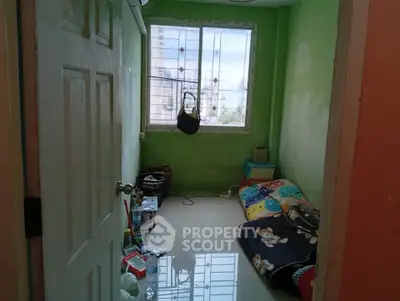 Cozy small bedroom with green walls and a window view, featuring a simple bed setup and minimal decor.