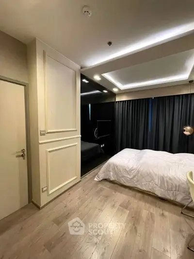 Modern bedroom with elegant lighting and wooden flooring, featuring a cozy bed and stylish decor.
