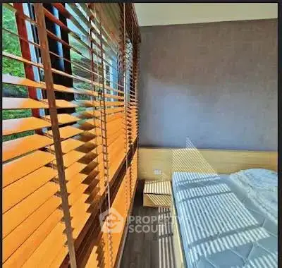 Bright bedroom with large windows and wooden blinds, offering a cozy and inviting atmosphere.