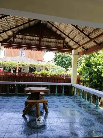 Charming outdoor patio with rustic wooden furniture and tiled flooring, perfect for relaxation.