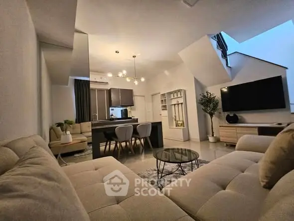 Modern living room with open kitchen, stylish furniture, and elegant lighting