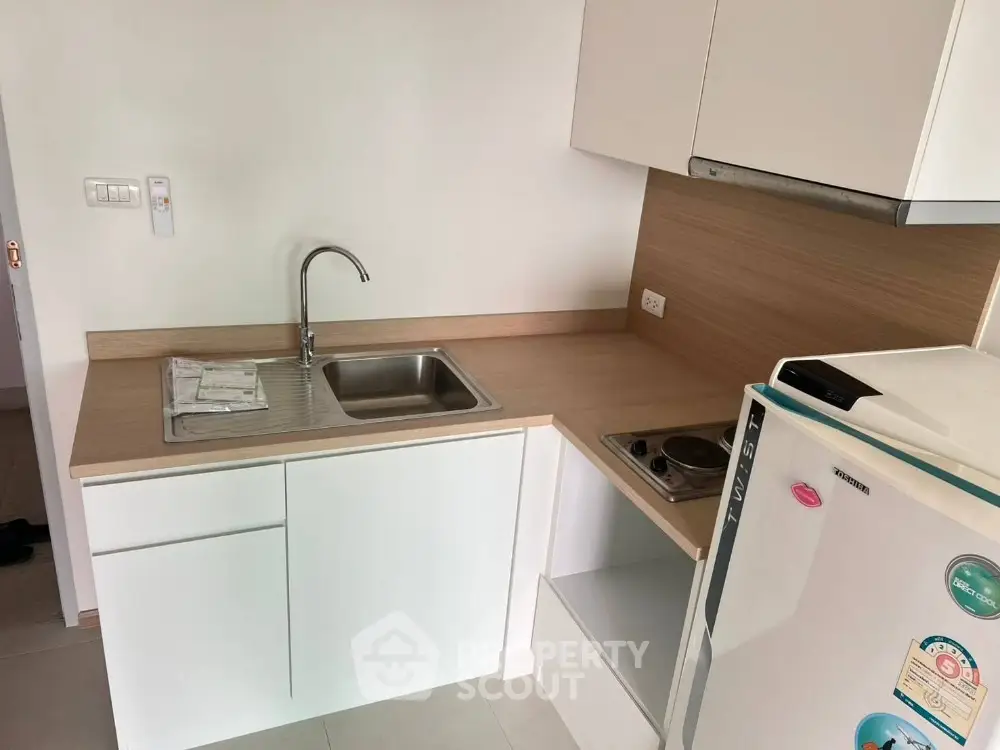 Modern compact kitchen with sleek white cabinets and built-in electric stove