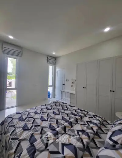 Bright and modern bedroom with stylish geometric bedding and ample natural light.