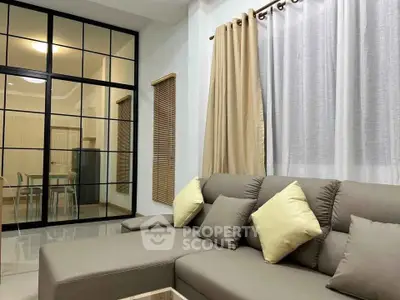 Modern living room with stylish sectional sofa and elegant glass partition.