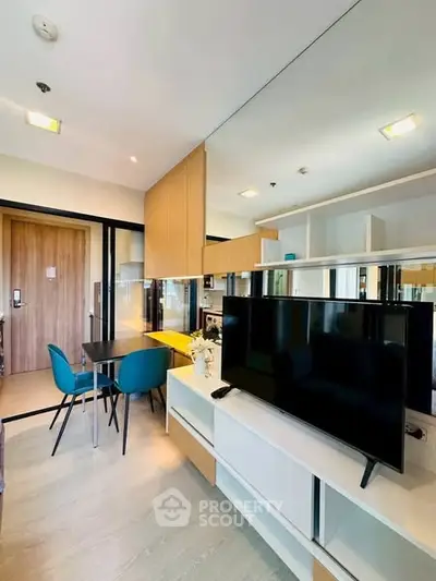 Modern living room with sleek TV unit and dining area, featuring stylish decor and ample natural light.