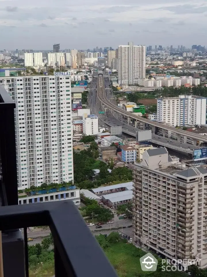 Stunning cityscape view from high-rise balcony overlooking urban skyline and highway.