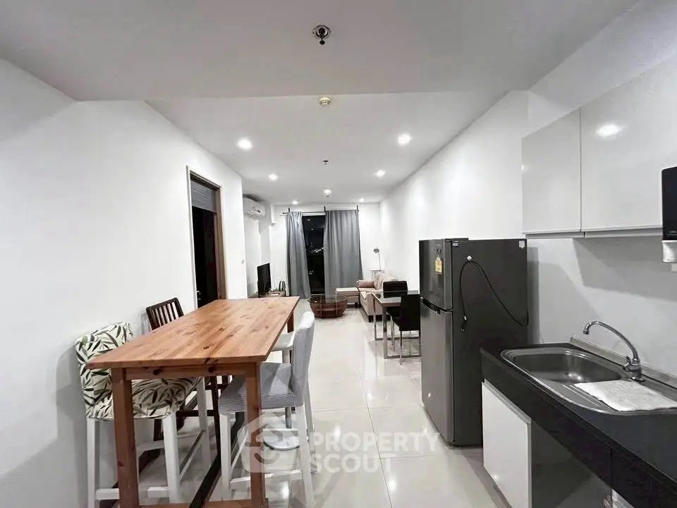 Modern open-layout kitchen and living area with sleek design and ample lighting.