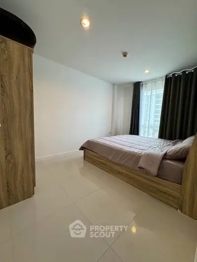 Spacious bedroom with modern wooden furniture and large window for natural light.