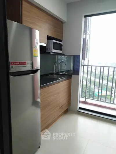 Modern kitchen with sleek appliances and balcony view in urban apartment