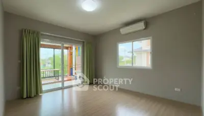 Spacious empty room with wooden flooring and balcony access in modern home.