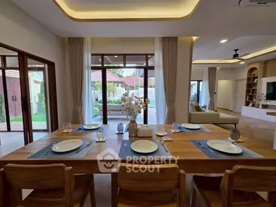 Elegant dining area with wooden table set, open layout to spacious living room and garden view.