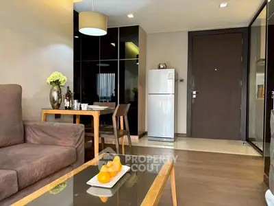 Modern living room with dining area and sleek kitchen appliances in a cozy apartment.