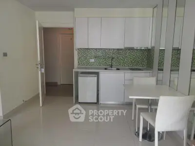 Modern kitchen with sleek white cabinets and dining area in open layout apartment.