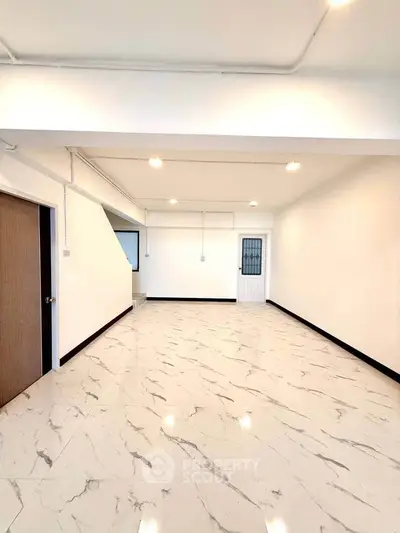 Spacious empty room with marble flooring and bright lighting, ideal for customization.