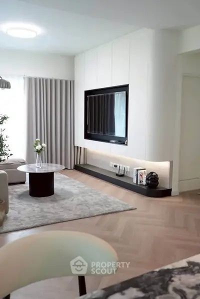 Modern living room with sleek design, featuring a wall-mounted TV, elegant furniture, and stylish decor.