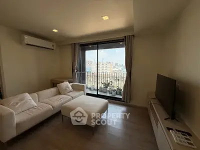 Modern living room with city view, cozy white sofa, and sleek TV setup.
