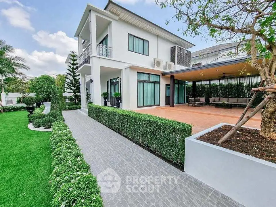 Stunning modern two-story home with lush garden and spacious patio, perfect for outdoor living.