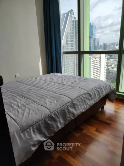 Modern bedroom with stunning city view and large windows in high-rise apartment.