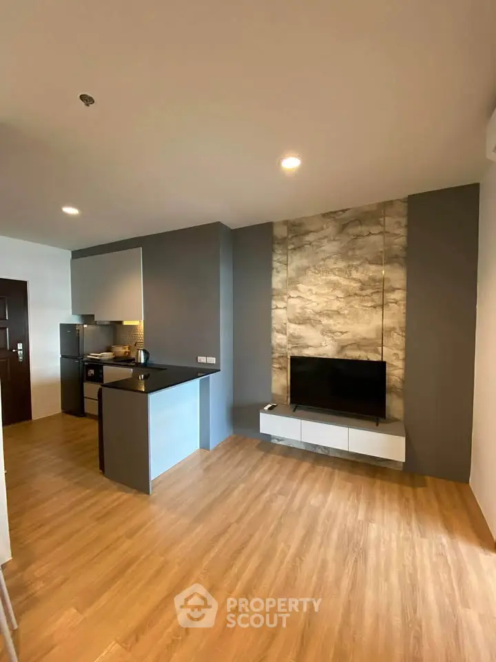 Modern open-layout living room with sleek kitchen and stylish TV wall design.