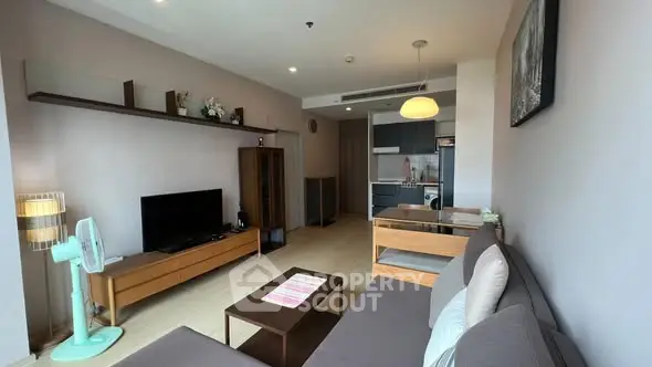 Modern living room with open kitchen, stylish furniture, and natural light.