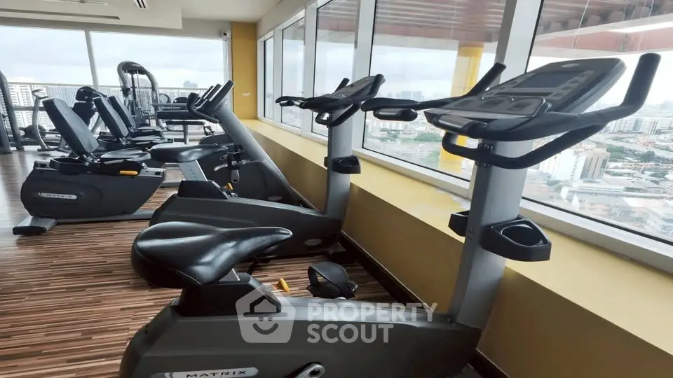 Modern gym with city view, featuring state-of-the-art exercise bikes and equipment, ideal for fitness enthusiasts.