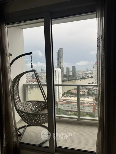 Stunning high-rise balcony view with cityscape and river, featuring a cozy hanging chair for relaxation.