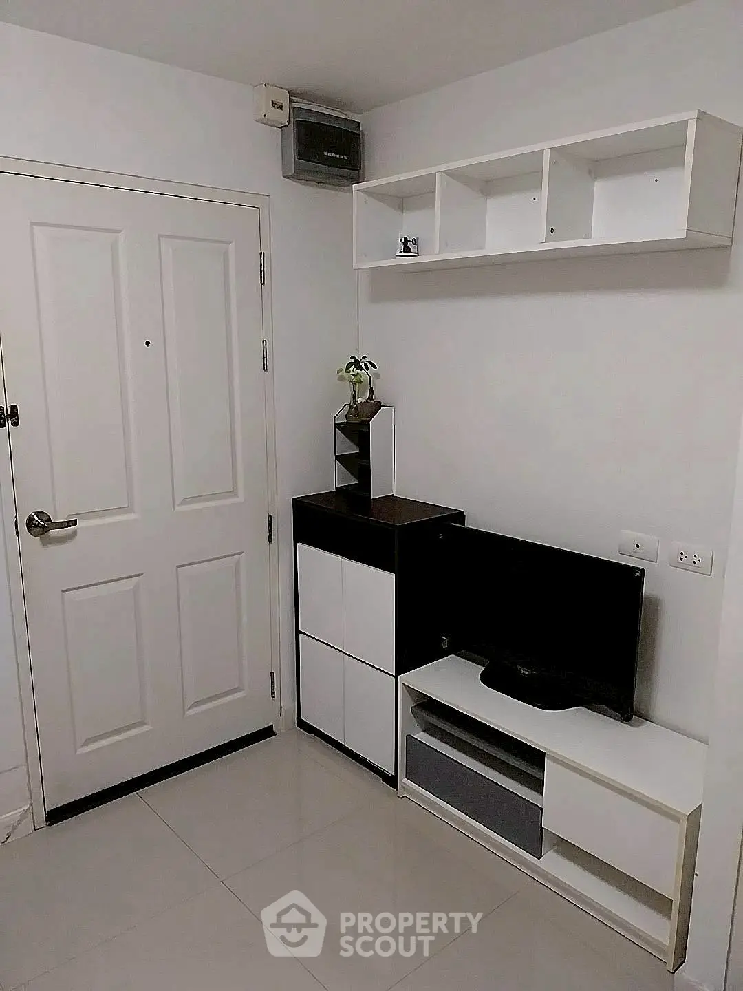 Modern minimalist living room with sleek white furniture and wall-mounted storage.