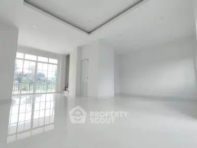 Spacious modern living room with large windows and glossy white floors.