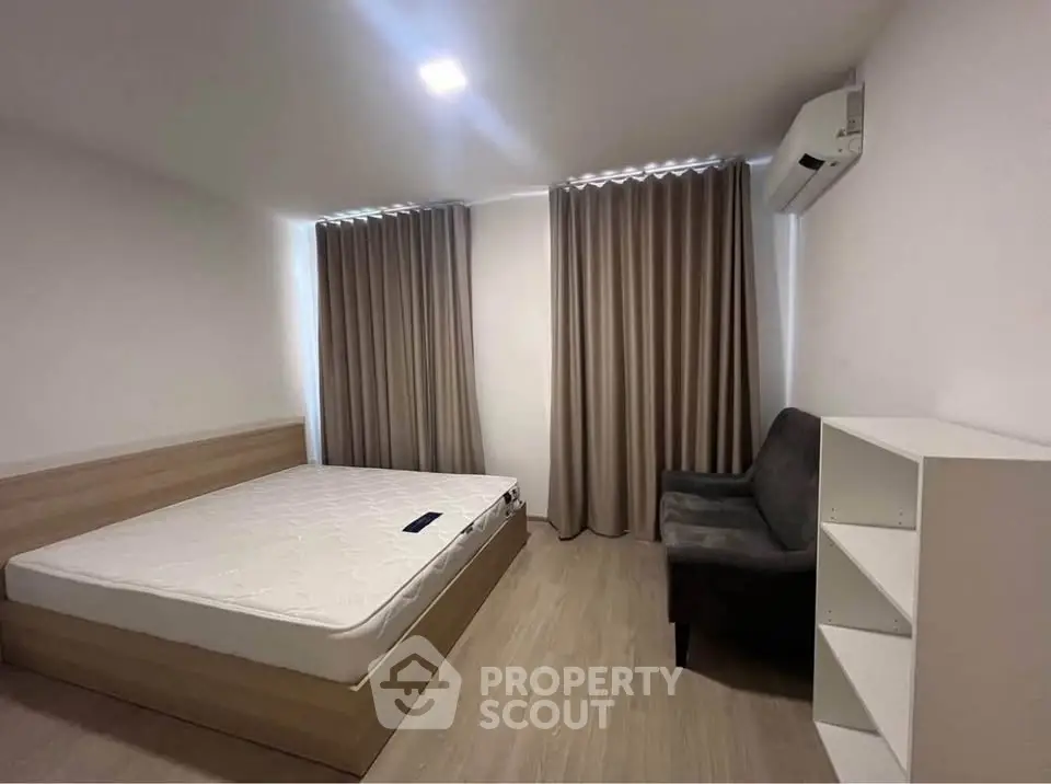 Modern minimalist bedroom with wooden flooring, cozy bed, and elegant curtains.