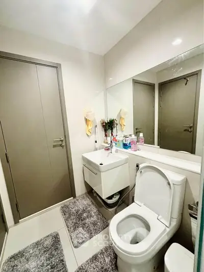 Modern bathroom with sleek fixtures and neutral tones, featuring a large mirror and stylish decor.