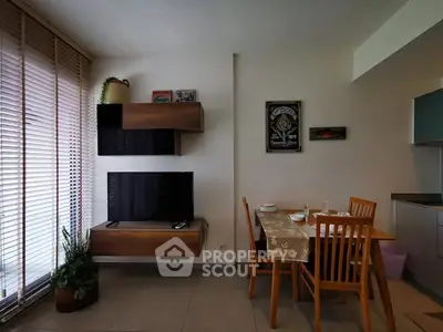 Modern living room with stylish furniture and dining area, featuring a wall-mounted TV and large windows.