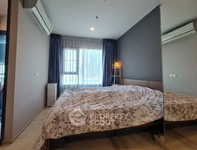 Modern bedroom with large window and stylish decor in urban apartment.