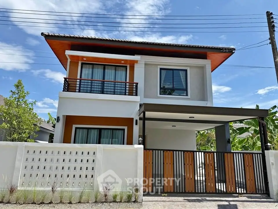 Modern two-story house with sleek design and gated entrance under a clear blue sky.