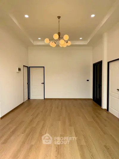 Spacious empty room with elegant chandelier and wooden flooring