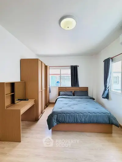 Modern bedroom with wooden furniture and natural light, perfect for cozy living.