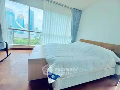 Spacious bedroom with large window offering stunning city view in modern apartment.