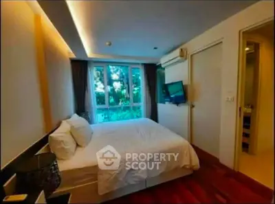Cozy bedroom with modern design and large window offering natural light and garden view.