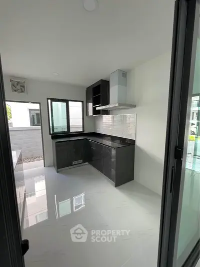 Modern kitchen with sleek black cabinets and glossy white tiles in a contemporary home