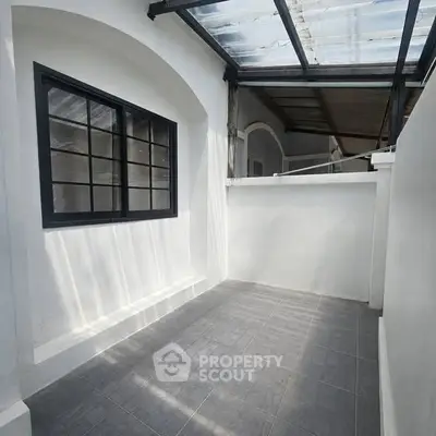 Charming small patio with modern glass roof and elegant arched window, perfect for cozy outdoor relaxation.