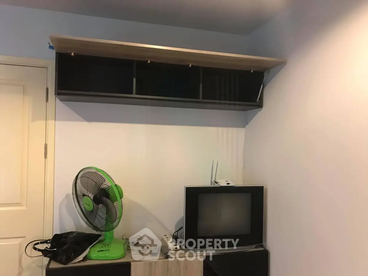 Cozy room with vintage TV and fan, featuring modern wall-mounted shelf for extra storage.