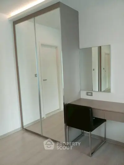 Modern bedroom with sleek mirrored wardrobe and stylish vanity desk