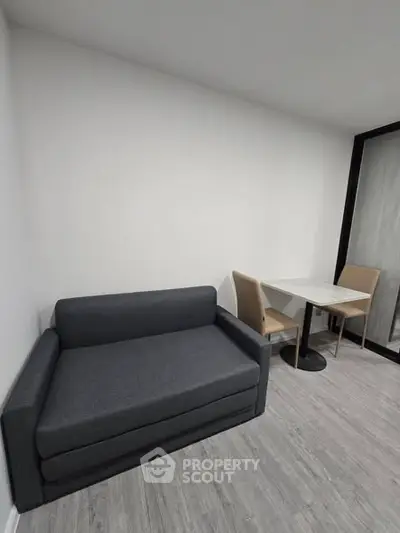 Modern minimalist living room with sleek gray sofa and compact dining area