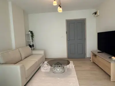 Modern living room with beige sofa, stylish coffee table, and wall-mounted TV for cozy relaxation.