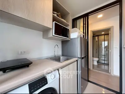 Modern kitchen with sleek appliances and open layout leading to a stylish bathroom.