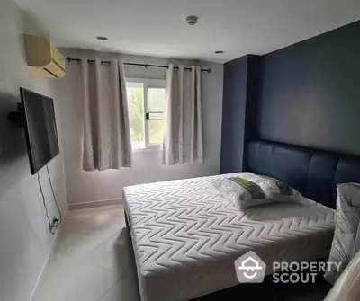 Modern bedroom with a large bed featuring a stylish headboard, wall-mounted TV, and ample natural light from the window, ideal for relaxation.