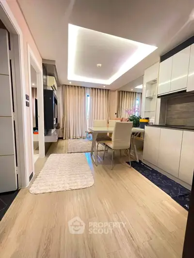 Modern open-plan living and dining area with sleek kitchen design and elegant lighting.