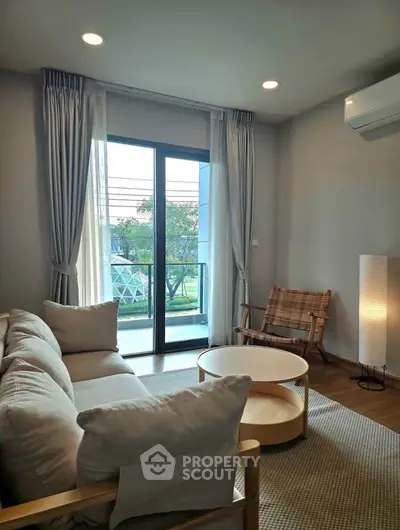 Modern living room with cozy seating and balcony view, perfect for relaxation.