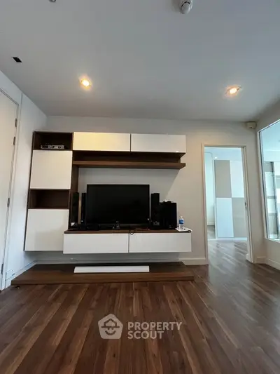 Modern living room with sleek wooden flooring and stylish TV unit, perfect for contemporary living.