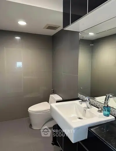 Modern bathroom with sleek fixtures and elegant design, featuring a large mirror and contemporary sink.